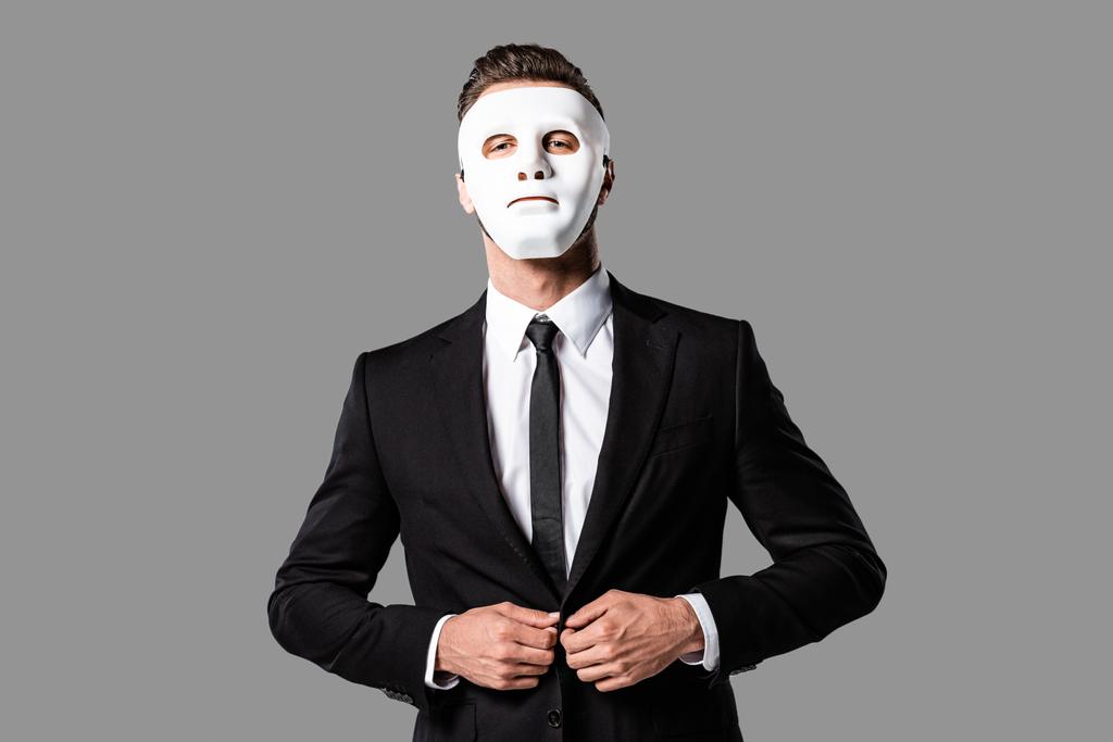 σίγουρος όμορφος επιχειρηματίας με μαύρο κοστούμι και λευκή μάσκα απομονώνεται σε γκρι - Φωτογραφία, εικόνα