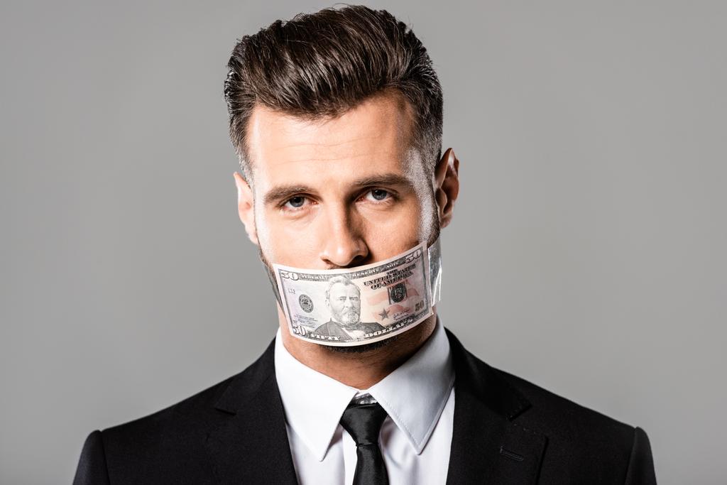 liikemies mustassa puvussa dollarin seteli suussa eristetty harmaalla
 - Valokuva, kuva
