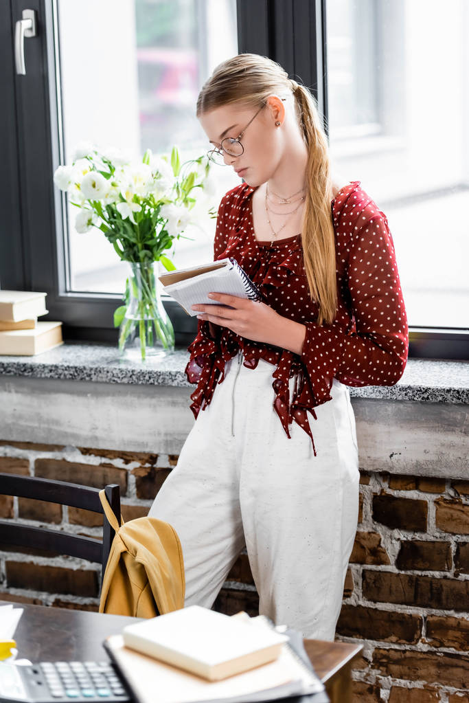 attractive student in glasses writing in notebook in apartment  - Photo, Image