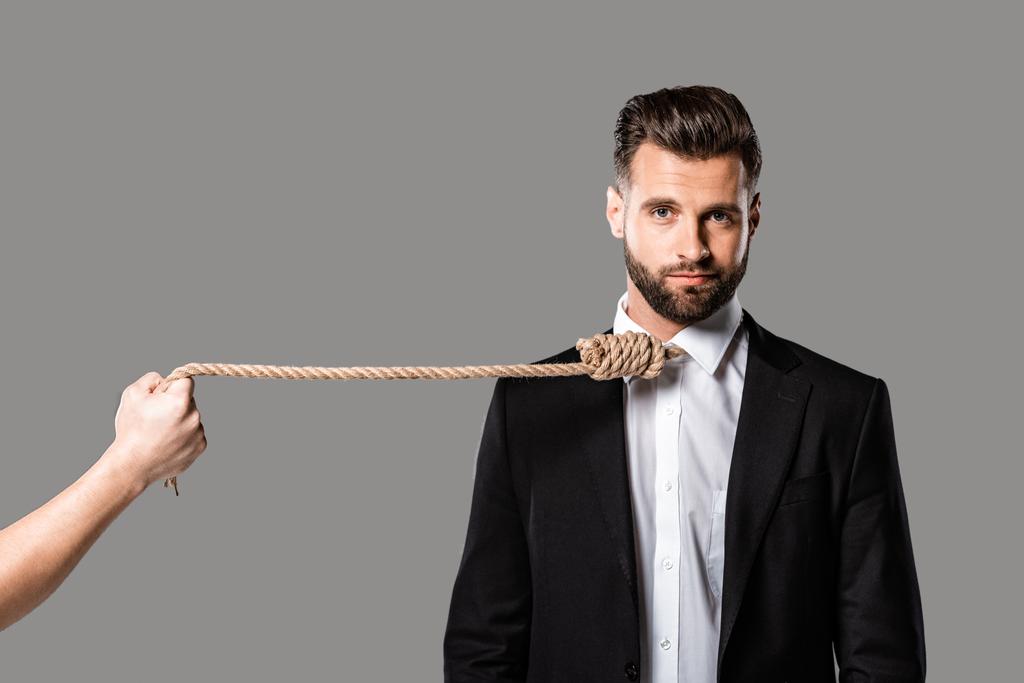 depressed businessman in black suit with noose on neck near murderer with rope isolated on grey - Photo, Image