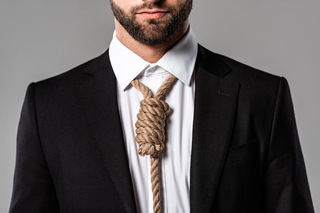 Teilansicht des depressiven Geschäftsmannes im schwarzen Anzug mit Schlinge um den Hals isoliert auf grau - Foto, Bild