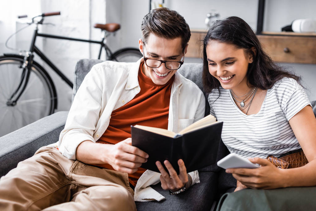 boldog, multikulturális diákok mosolyogva és olvasás könyvet az apartmanban  - Fotó, kép