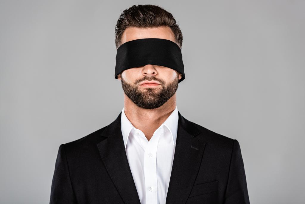 бородатый красивый бизнесмен с завязанными глазами в черном костюме, изолированный от серого
 - Фото, изображение
