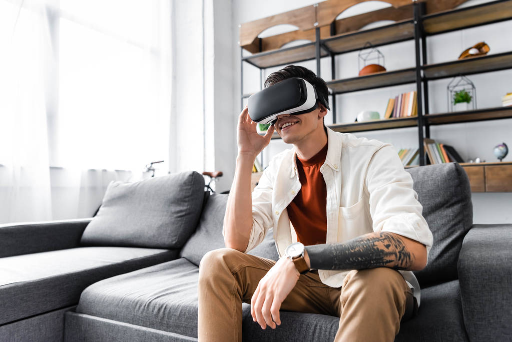 mies virtuaalitodellisuus kuulokkeet istuu sohvalla asunnossa
  - Valokuva, kuva