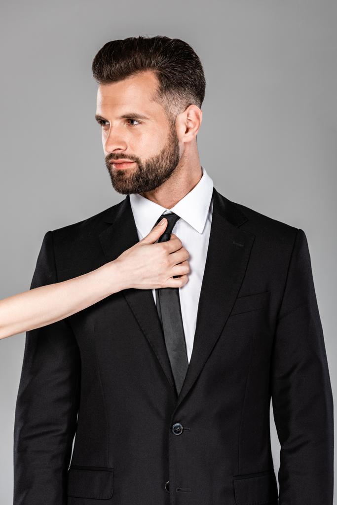 woman touching tie on successful businessman in black suit isolated on grey - Photo, Image
