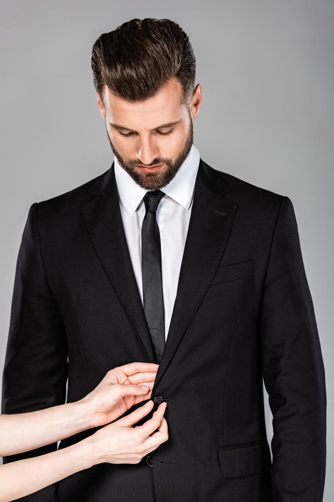 bottone di fissaggio donna sul vestito nero uomo d'affari di successo isolato su grigio
 - Foto, immagini