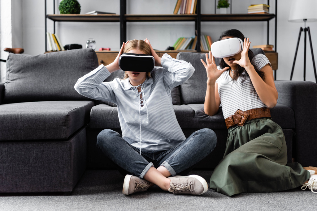 amigos multiculturales con auriculares de realidad virtual sentados en el piso en el apartamento
  - Foto, Imagen