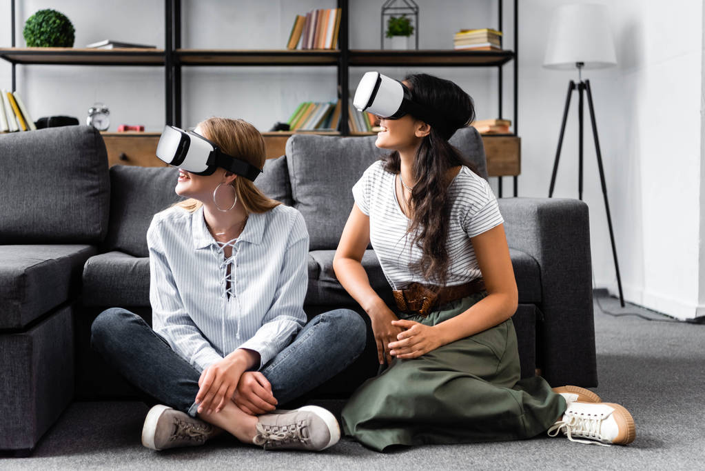 amigos multiculturales con auriculares de realidad virtual sentados en el piso en el apartamento
  - Foto, imagen