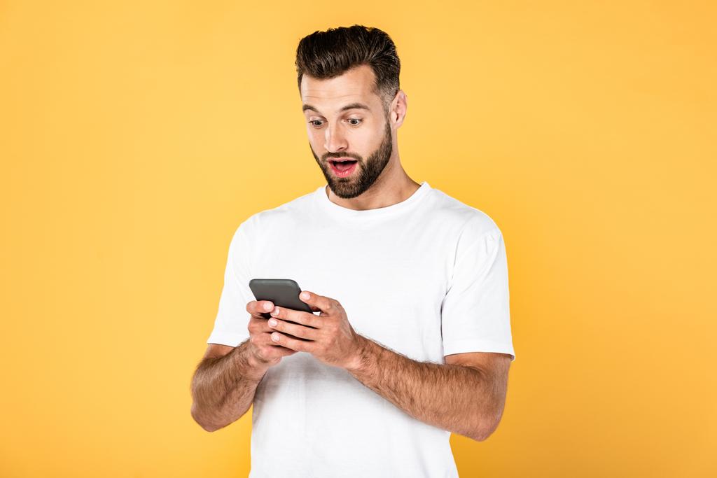 animado bonito homem em branco t-shirt usando smartphone isolado no amarelo
 - Foto, Imagem