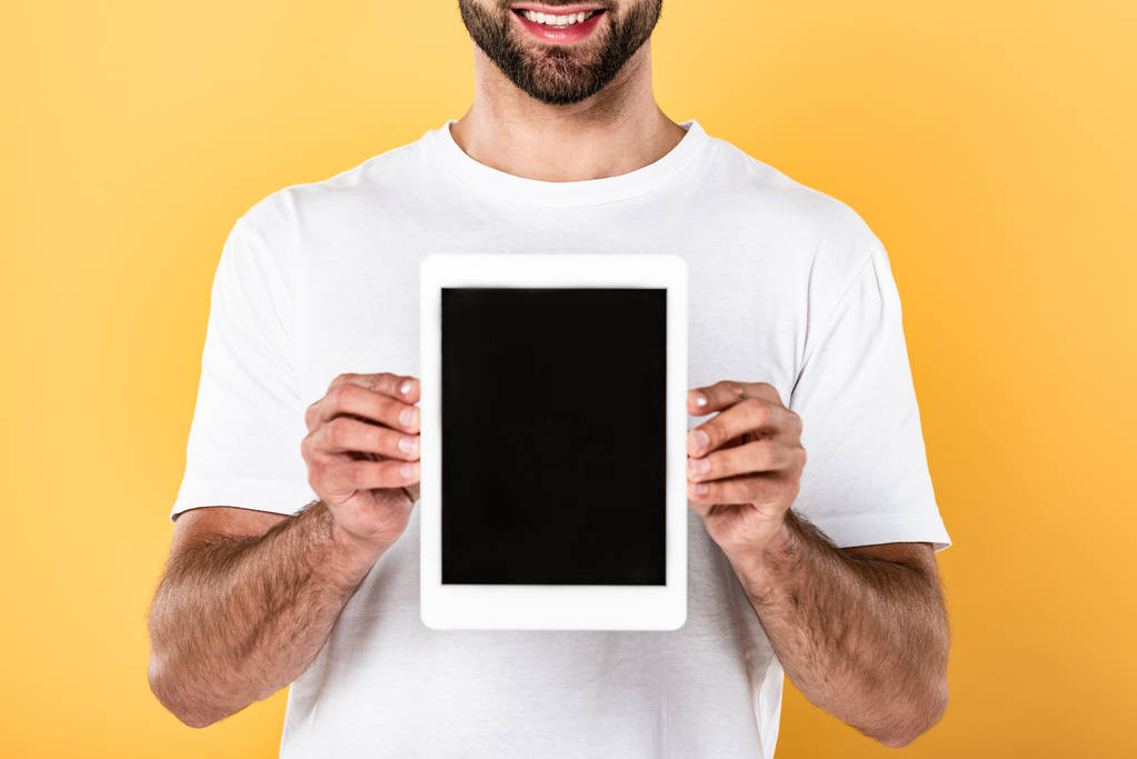 vue partielle de l'homme souriant en t-shirt blanc montrant tablette numérique avec écran blanc isolé sur jaune
 - Photo, image