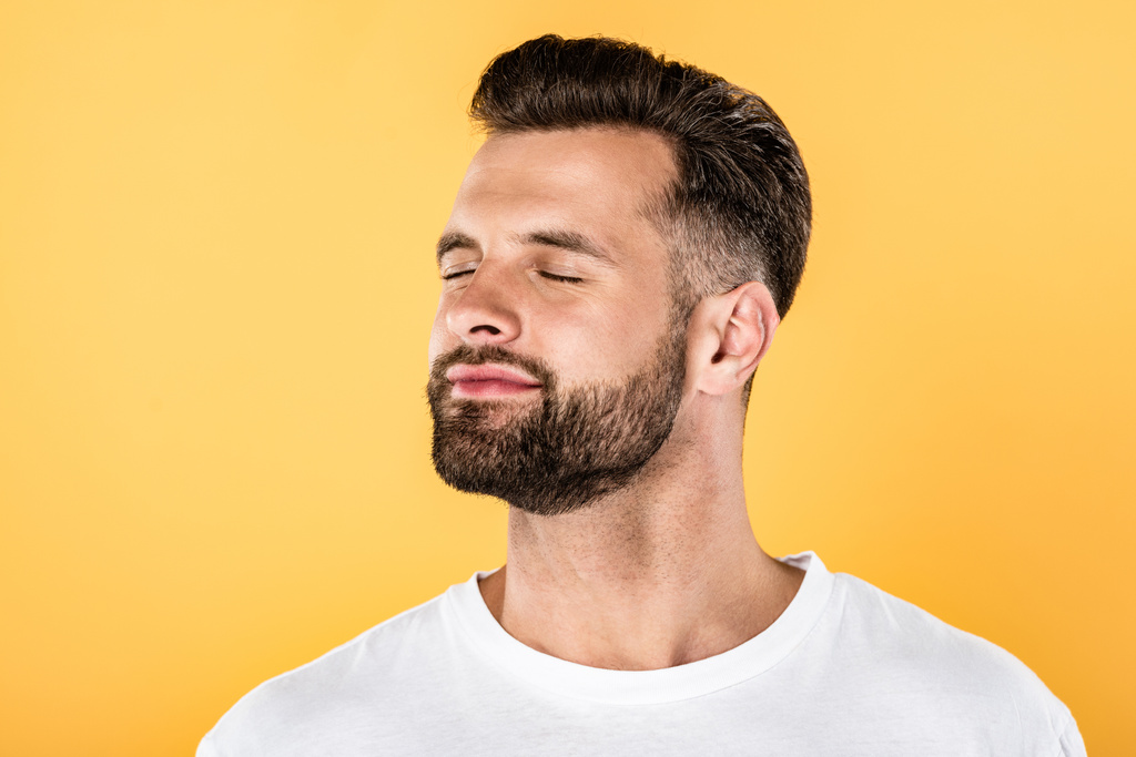 joyful handsome man in white t-shirt with closed eyes isolated on yellow - Photo, Image