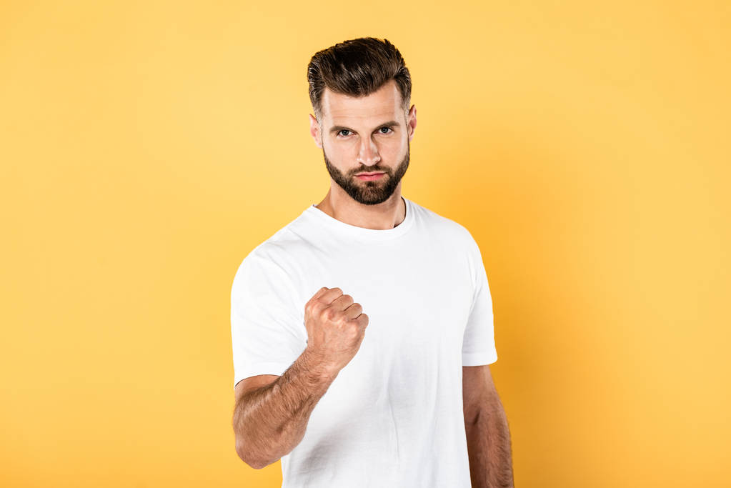 homme beau en colère en t-shirt blanc montrant poing isolé sur jaune
 - Photo, image