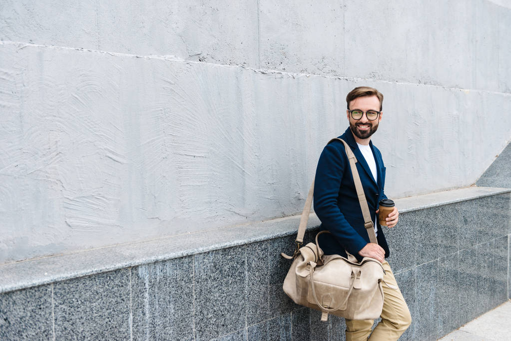 Tyytyväisen liikemiehen muotokuva silmälaseissa, jotka juovat kahvia paperimukista ja kantavat laukkua
 - Valokuva, kuva
