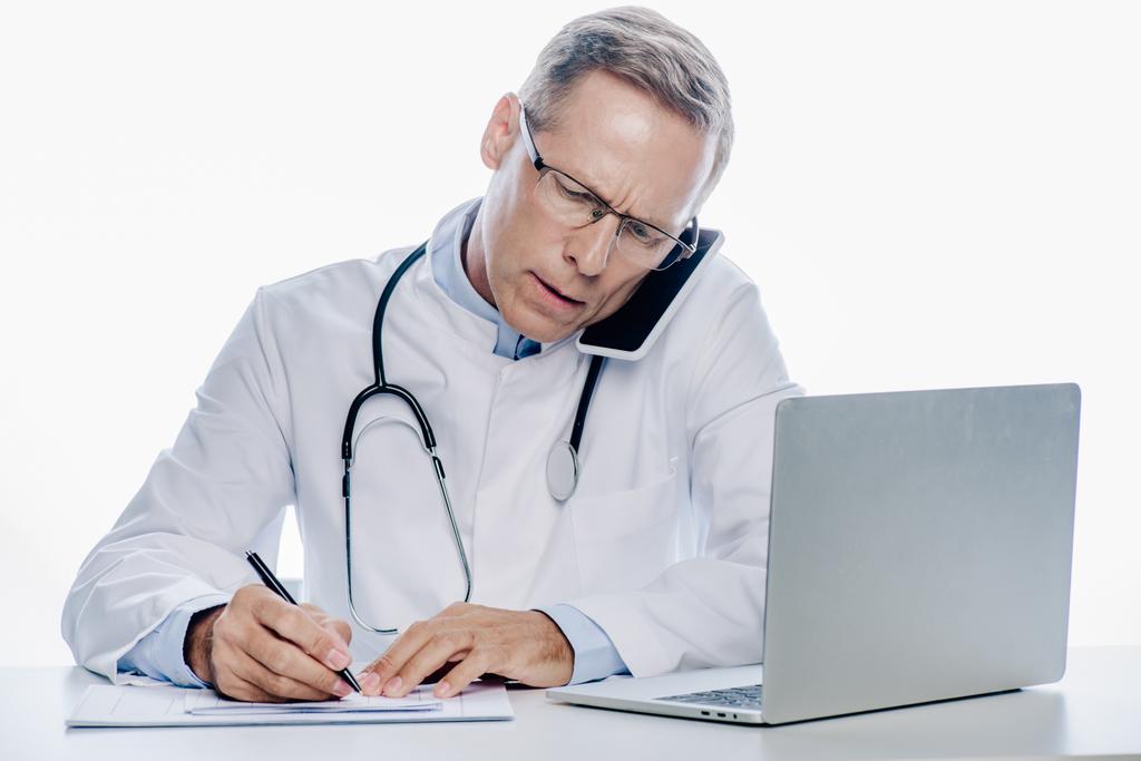 όμορφος γιατρός με λευκό παλτό μιλάει στο smartphone και γραφή απομονωθεί σε λευκό - Φωτογραφία, εικόνα