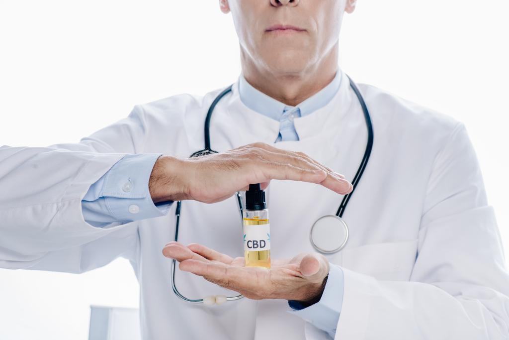 oříznutý pohled na doktora v bílém plášti s konopným olejem izolovaným na bílém - Fotografie, Obrázek