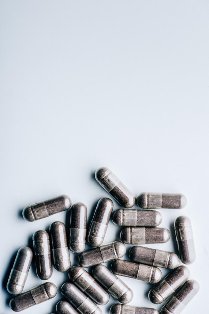 vista superior de píldoras negras sobre fondo blanco con espacio de copia
  - Foto, Imagen