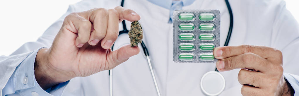 Panoramaaufnahme eines Arztes in weißem Kittel mit medizinischem Cannabis und Tabletten isoliert auf weißem Grund  - Foto, Bild