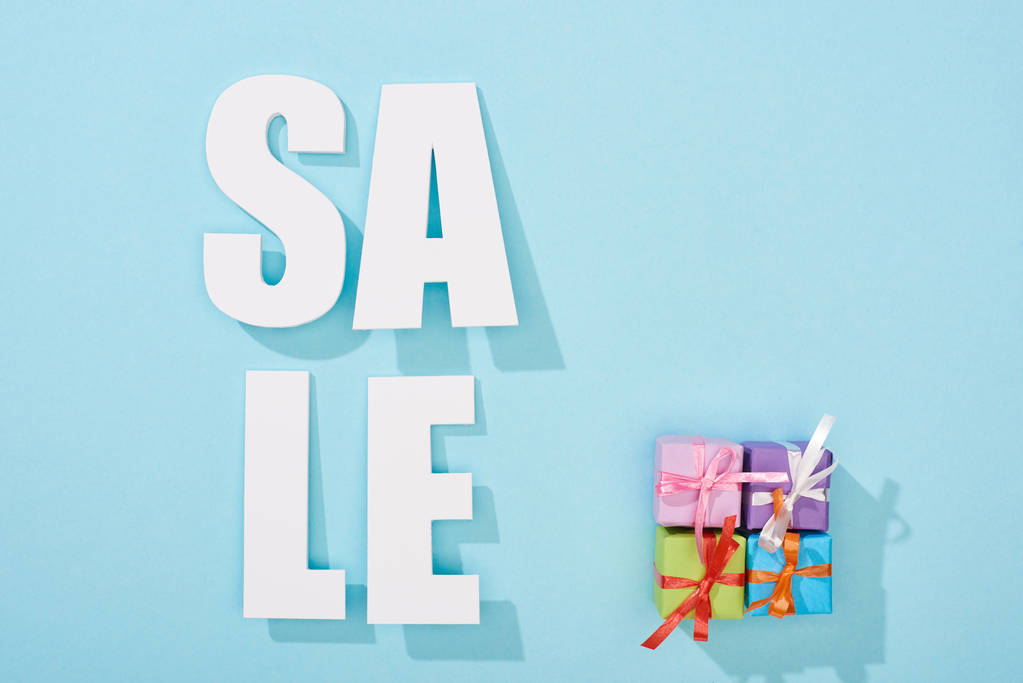 top view of white sale lettering near festive gift boxes on blue background - Photo, Image