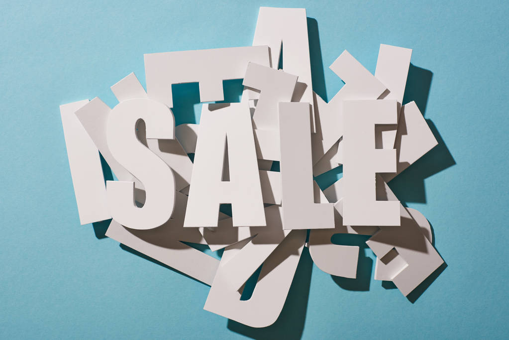 Top uitzicht van witte verkoop belettering op stapel van letters op blauwe achtergrond - Foto, afbeelding