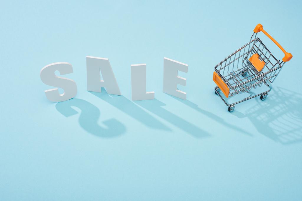 ylhäältä näkymä valkoinen myynti kirjaimet lähellä ostoskärry sinisellä pohjalla
 - Valokuva, kuva
