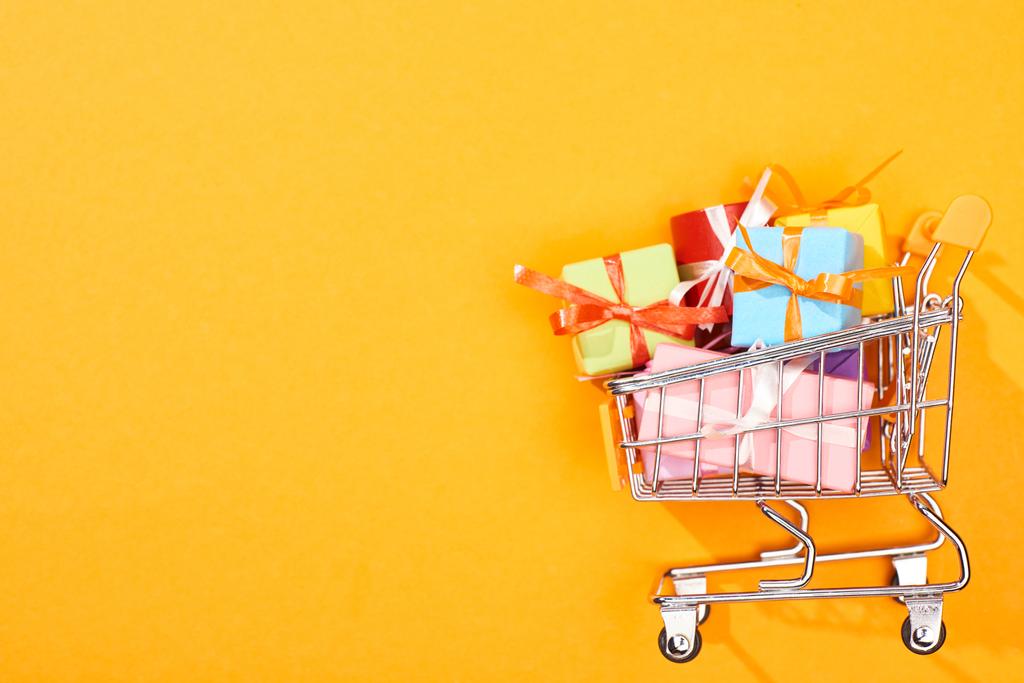 vista superior do carrinho de compras com presentes no fundo laranja brilhante
 - Foto, Imagem