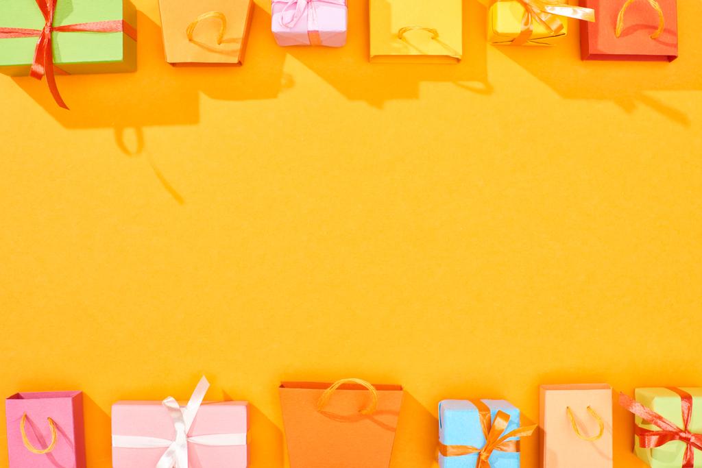 vista superior de coloridas bolsas de compras y regalos sobre fondo naranja brillante con espacio de copia
 - Foto, imagen