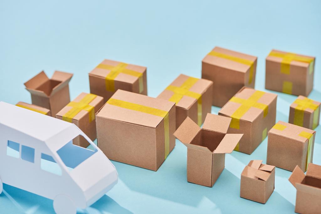 cajas de cartón cerca del modelo de furgoneta sobre fondo azul con espacio de copia
 - Foto, imagen