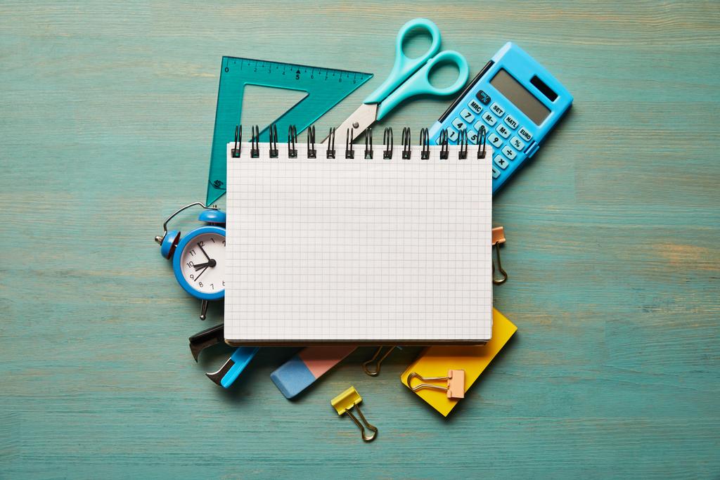 vista superior del cuaderno en blanco cerca de los útiles escolares azules en la mesa de madera turquesa
 - Foto, Imagen
