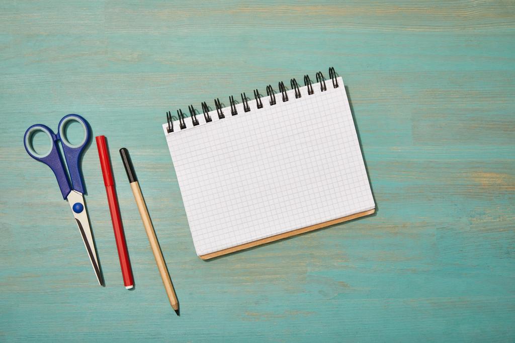 bovenaanzicht van lege notebook in de buurt van potlood, schaar en vilt pen op houten bureau - Foto, afbeelding