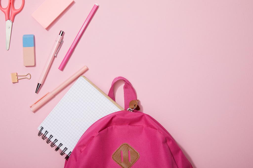 вид зверху на розкидані шкільні приладдя та порожній блокнот біля рюкзака ізольовані на рожевому
 - Фото, зображення