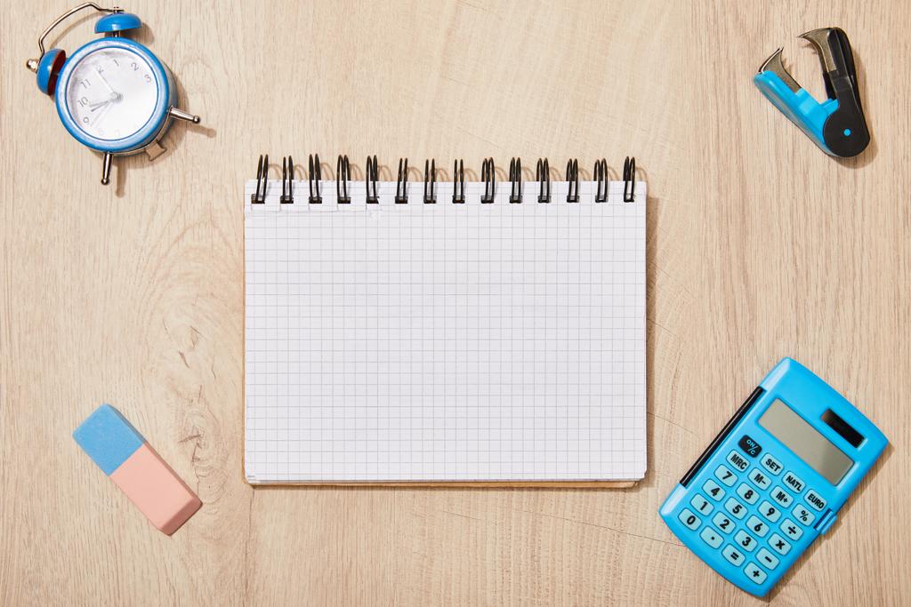 Widok z góry pustego notebooka w pobliżu gumy, zegara i kalkulatora na drewnianym biurku - Zdjęcie, obraz