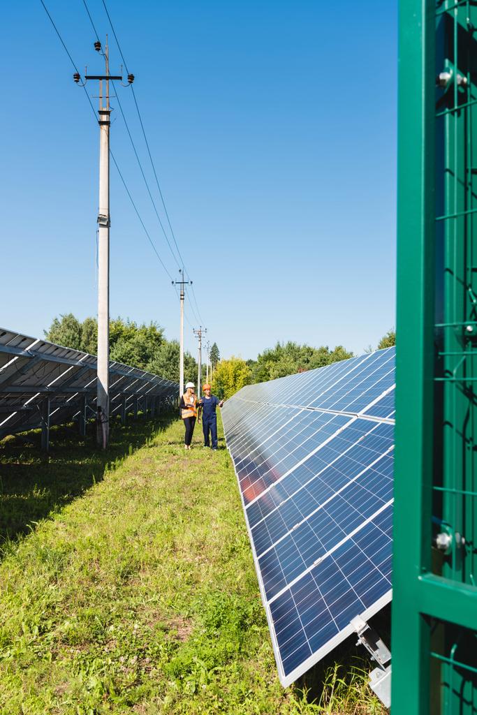μηχανικός και επιχειρηματίας που μιλούν και περπατούν κοντά σε μπαταρίες ηλιακής ενέργειας  - Φωτογραφία, εικόνα