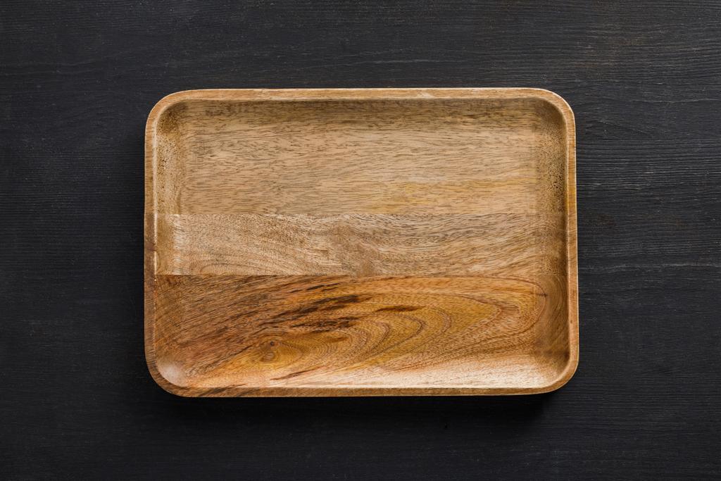 Vista superior do prato vazio de madeira marrom na superfície escura
 - Foto, Imagem