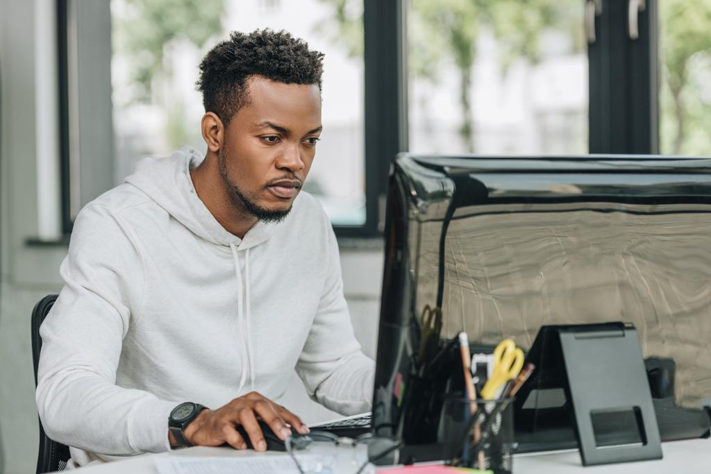 προσεκτικός Αφρικανός Αμερικανός προγραμματιστής που εργάζεται σε υπολογιστή στο γραφείο - Φωτογραφία, εικόνα