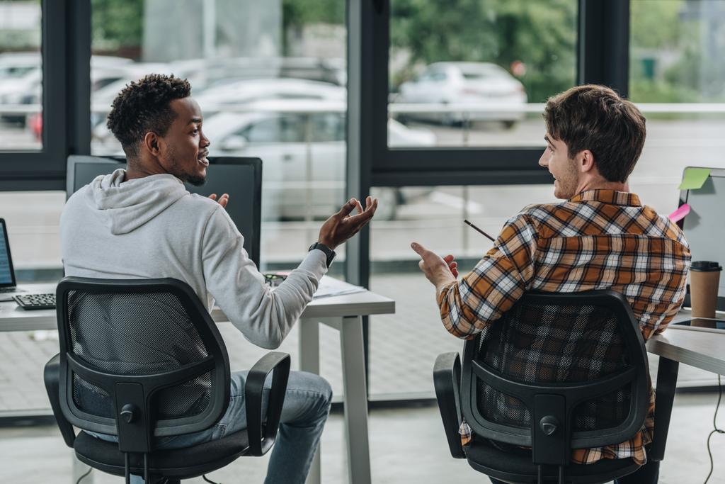Два молодых мультикультурных программиста жестом во время разговора в офисе
 - Фото, изображение