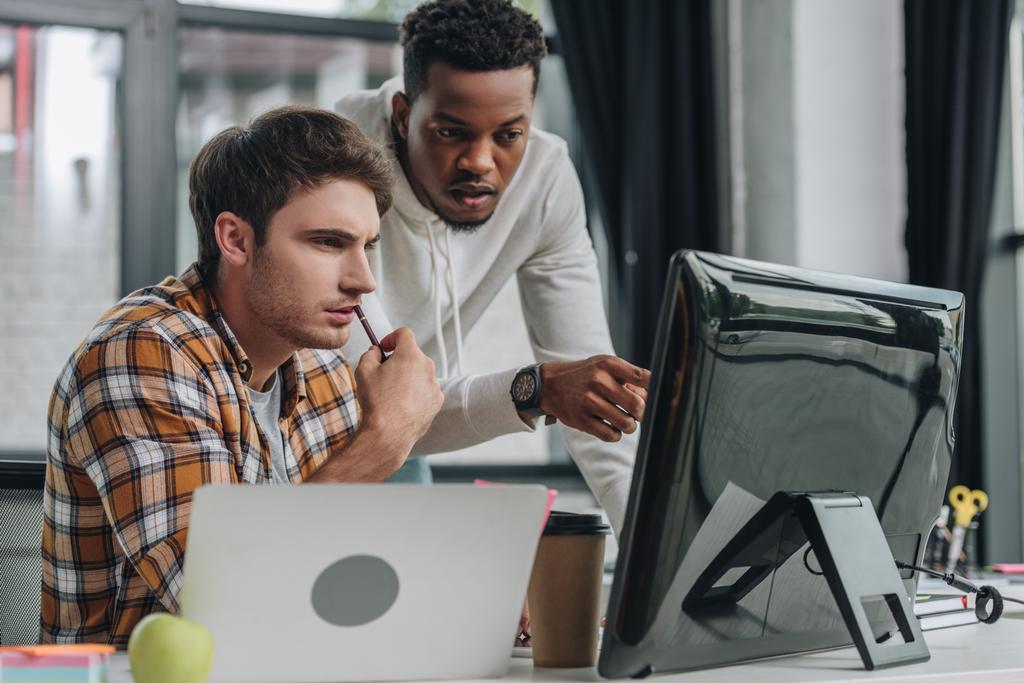 african american programmer pointing at computer monitor near serious colleague - Photo, Image