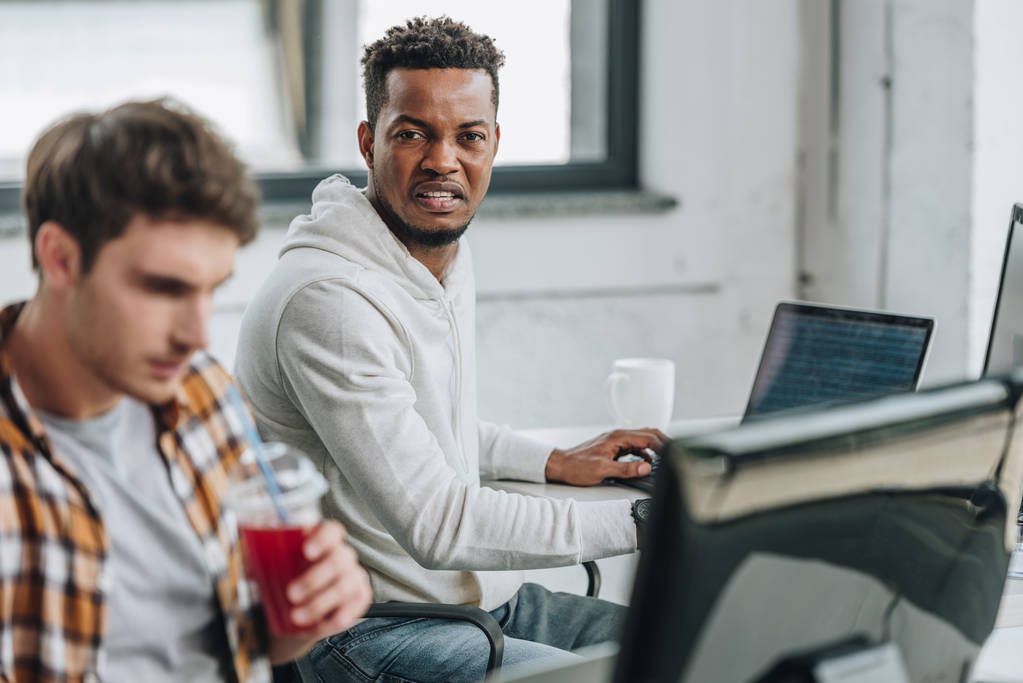 selective focus of angry african american programmer sitting near thoughtful colleague - Photo, Image