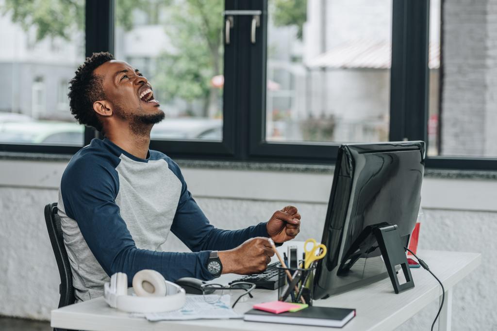 programmeur afro-américain en colère gestuelle tout en étant assis sur le lieu de travail dans le bureau
 - Photo, image
