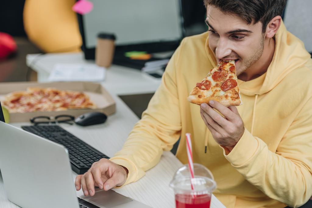 красивий програміст їсть піцу, сидячи на робочому місці в офісі
 - Фото, зображення