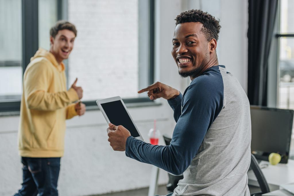 улыбающийся африканский американский программист указывая пальцем на цифровой планшет рядом с коллегой показывая большой палец вверх
 - Фото, изображение