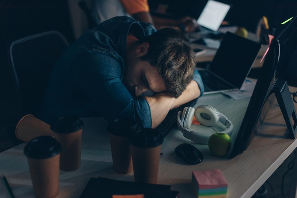 junger, erschöpfter Programmierer schläft nachts am Arbeitsplatz im Büro - Foto, Bild