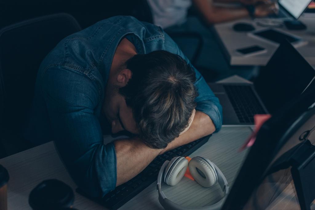 молодий виснажений програміст спить на клавіатурі вночі в офісі
 - Фото, зображення