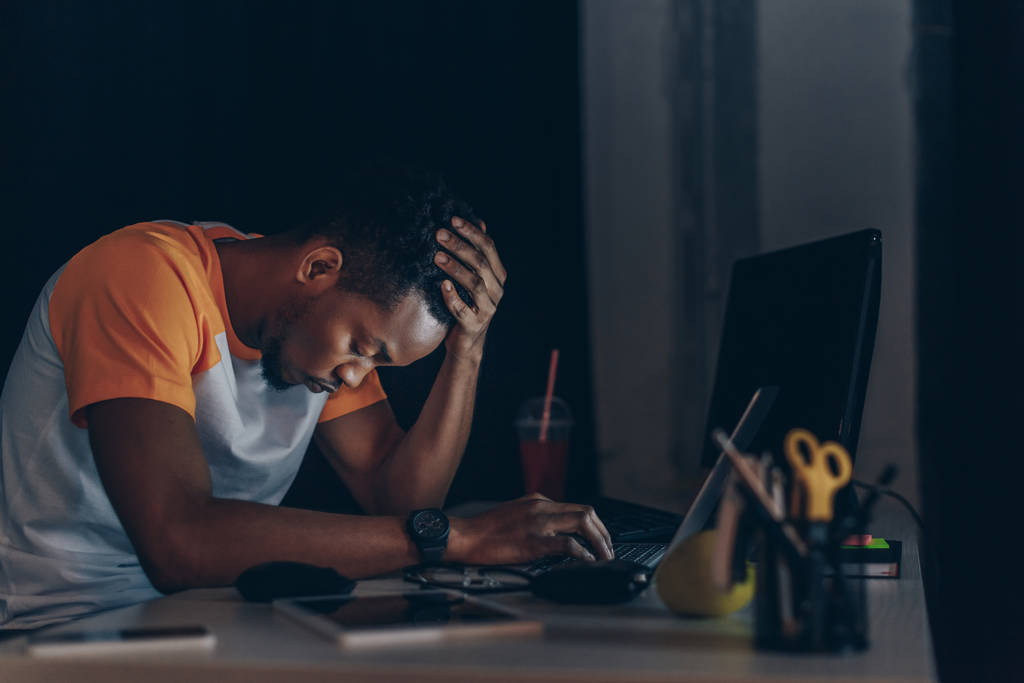 programador afroamericano soñoliento sentado en el lugar de trabajo con los ojos cerrados
  - Foto, imagen