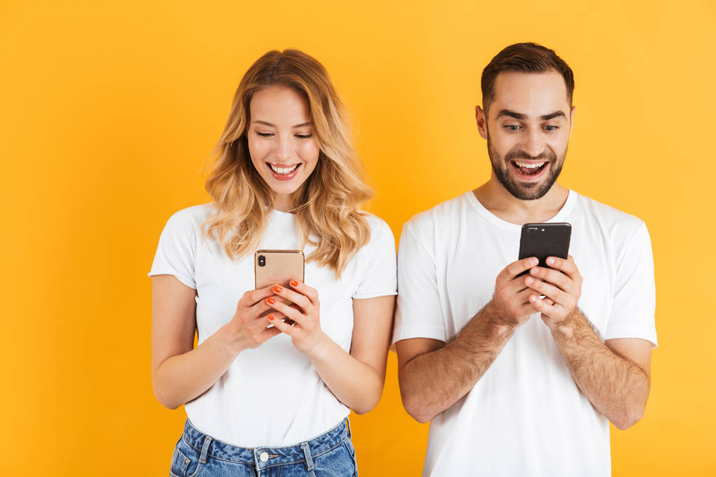 Birlikte cep telefonları tutarken gülümseyen güzel çift erkek ve kadın Görüntü - Fotoğraf, Görsel