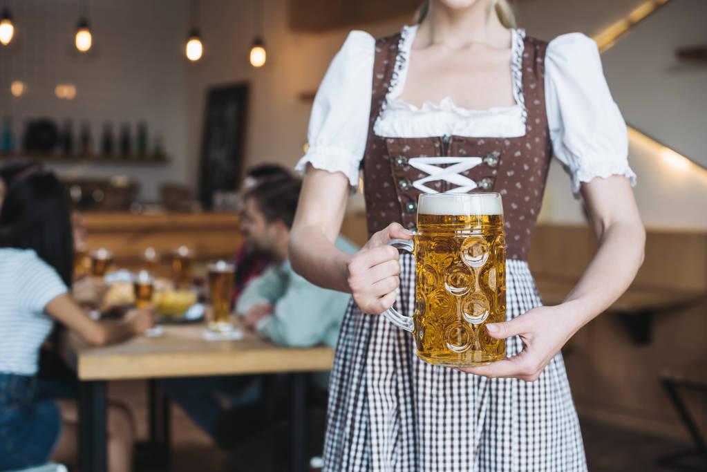 pohled na číšnici v německém národním kostýmu s džbánkem lehkého piva  - Fotografie, Obrázek