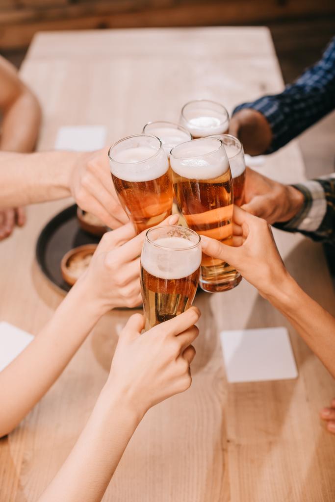 vista parcial de amigos multiculturales tintineo vasos con cerveza lager en el pub
 - Foto, Imagen