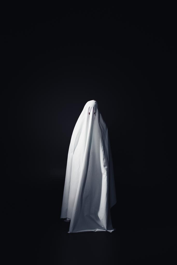 φρικτό φάντασμα σε λευκό σεντόνι απομονωθεί σε μαύρο με χώρο αντιγραφής - Φωτογραφία, εικόνα