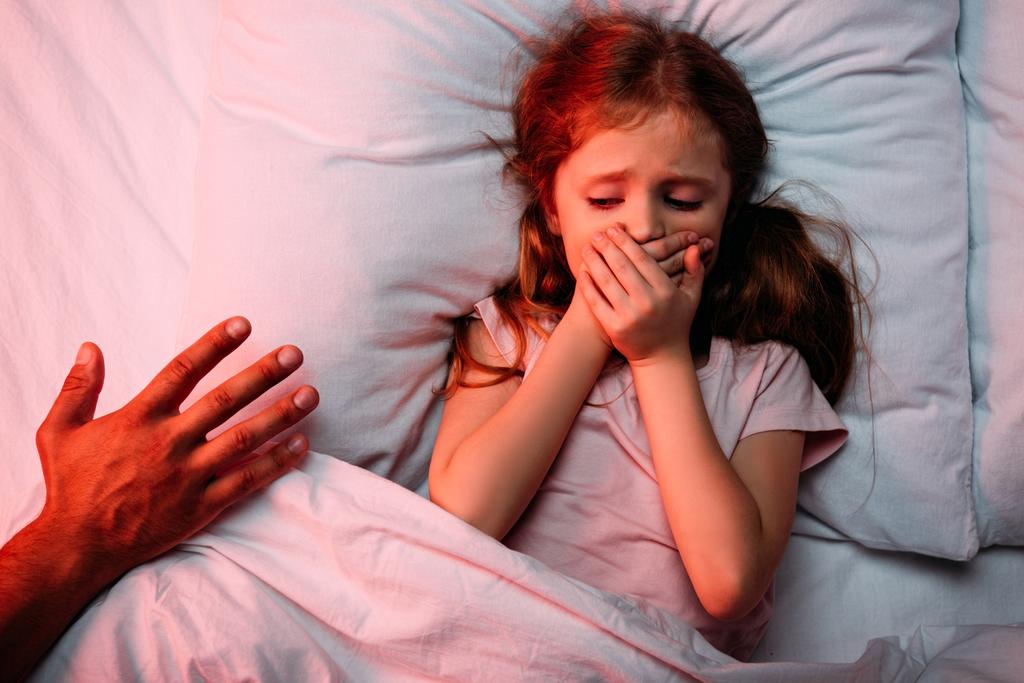 main masculine près de l'enfant effrayé couché dans le lit et montrant un signe de silence
 - Photo, image