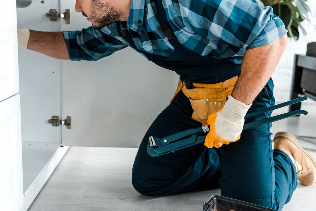 обрезанный вид бородатого ремонтника, держащего кусачки возле кухонного шкафа
  - Фото, изображение