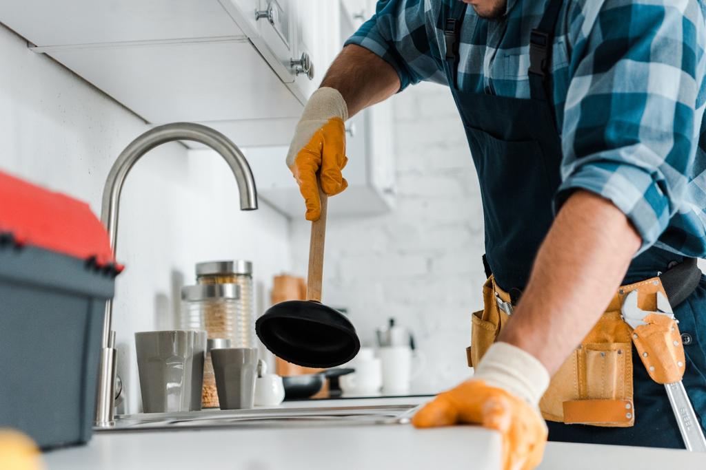 обрезанный вид ремонтника, держащего вантуз на кухне
 - Фото, изображение